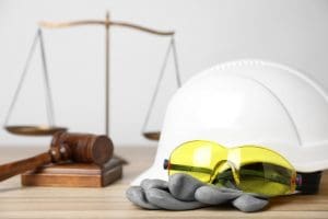 Workplace injury legal concept showing judge’s gavel, justice scales, and construction safety equipment.
